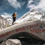 A Life Happens Outdoors Community Member on top of the iconic Everest Base Camp boulder during the LHO Everest Base Camp Trek