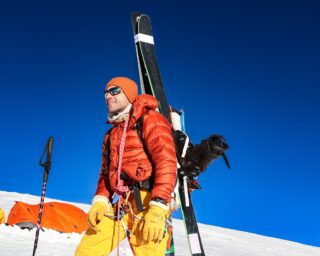 Ski mountaineer carrying skis and climbing equipment at Mera Peak high camp in Nepal.
