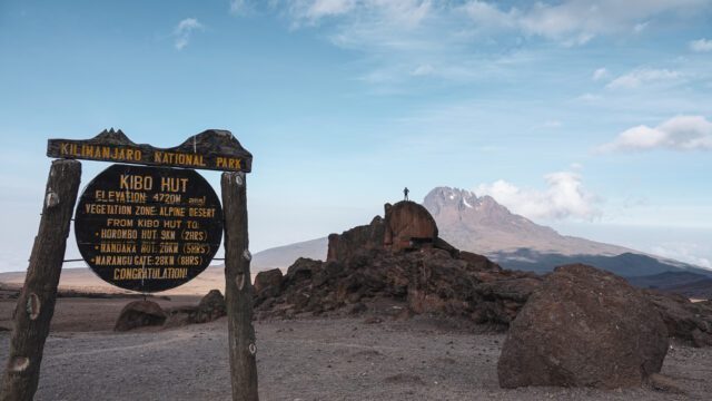 LHOer Edy Nasr standing on a rock at Kibo Hut with the Mawenzi Crater in the background on the Marangu Route during the Climb Kilimanjaro Expedition with the Life Happens Outdoors team.