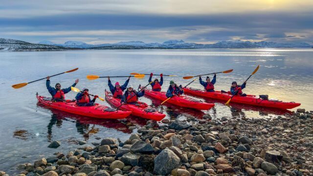 The Life Happens Outdoors team kayaking in the fjords of Norway's Arctic island of Senja during the Chase the Northern Lights adventure.