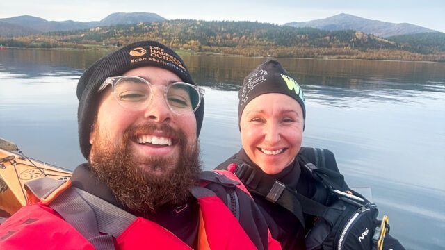 LHO Team Leader Bader Alsayyed and Hege, founder of Norwegian Wild, taking a selfie from the kayak with our coastal accommodation on the horizon during the Norway Arctic Adventure trip with the Life Happens Outdoors team.