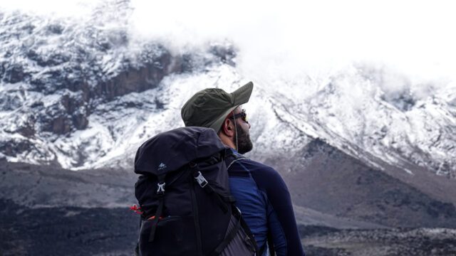 LHO Team Leader Jean Louis Moukarzel looking at the snow on the Kibo Crater from the top of the Baranco Wall on the Machame Route during the Climb Kilimanjaro expedition with the Life Happens Outdoors team.