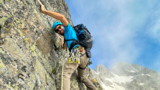 Gino Traboulsi climbing L'Index with the Aiguilles Rouges in the background during the Rock Climbing in Chamonix trip with the Life Happens Outdoors team.