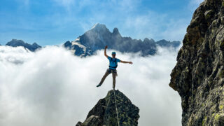 Gino Traboulsi on the summit of L'Index with the Aiguille Verte in the background during the Rock Climbing in Chamonix trip with the Life Happens Outdoors team.