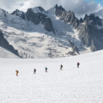 climbers on the mont blanc summit hike crossing a glacier.