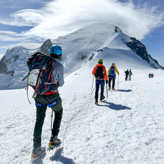 The Patel family climbing Mont Blanc at the top of the Dome du Goûter, with the summit of Mont Blanc clearly visible ahead under lenticular clouds, led by IFMGA guide Babis Marinidis during the Mont Blanc Summit Course with the Life Happens Outdoors team.