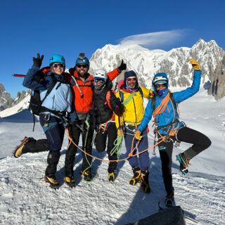 LHOers Roberto David, Carla Hachem, and Ranwa Zahr with IFMGA guides Babis Marinidis and Lucia Guichot Martin on the summit of Petit Flambeau during the training days of the Mont Blanc Summit Course, with the Mont Blanc summit visible in the background.