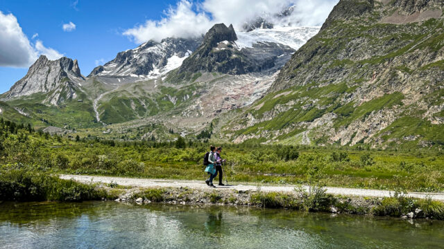 Ghida Arnaout, LHO Team Leader and co-founder, walks with an LHOer beside alpine lakes in Val Veny on the Italian side of the Tour du Mont Blanc, with the south face of Mont Blanc rising in the background.