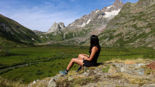Life Happens Outdoors trekker sitting at the entrance of Val Veny on the Tour du Mont Blanc trail, reflecting after completing the hardest climb toward Col de la Seigne.