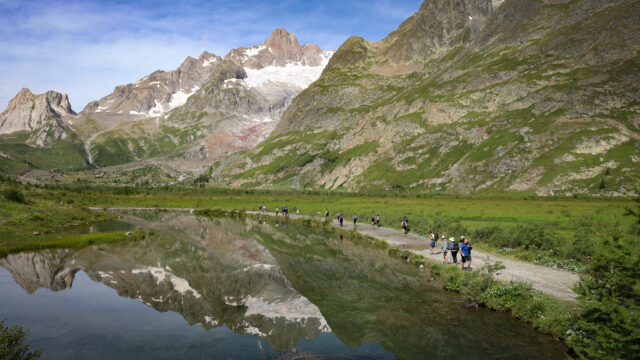 Life Happens Outdoors group hiking past alpine lakes in Italy's Val Veny on the Tour du Mont Blanc route to Col de la Seigne under clear blue skies