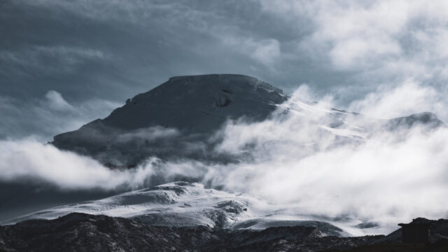 Mount Chimborazo emerging through the clouds at sunrise as seen from Whymper Refuge during a Life Happens Outdoors climbing expedition in Ecuador.