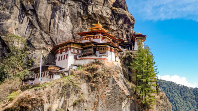 Panoramic view of Tiger’s Nest Monastery perched dramatically on a cliffside in Bhutan, surrounded by lush forest and misty mountain air.
