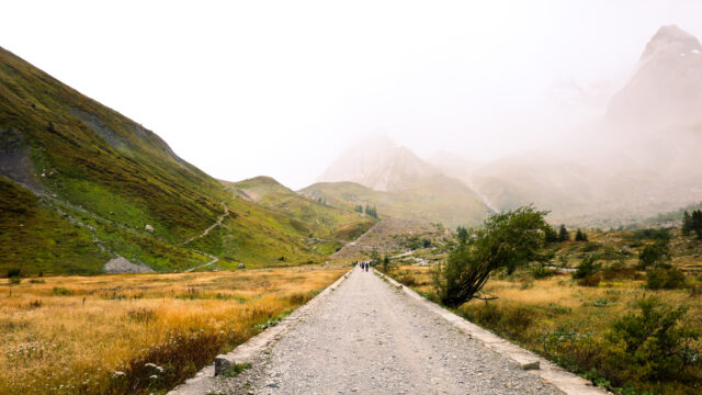 Hiker on the road to Col de la Seigne in Italy’s Val Veny, surrounded by mystical fog—an iconic section of the Tour du Mont Blanc trail.
