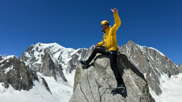 Life Happens Outdoors guide standing on the summit of Petit Flambeau with Mont Blanc rising majestically in the background under a clear alpine sky