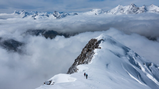 Life Happens Outdoors climbers ascending the Weissmies ridge with sweeping views of the Saas Valley and the dramatic peaks of the Mischabel range in the background