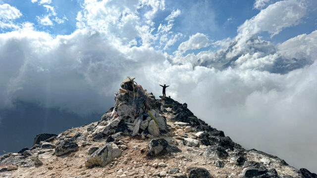 ChatGPT said: LHO climber trekking to Ama Dablam Camp 1 with dramatic clouds and sunlight breaking through, capturing the beauty of this iconic Himalayan climb.