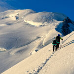 LHO team climbing above the second mogul on Mont Blanc just after sunrise, making their way toward the summit on the classic Gouter route.