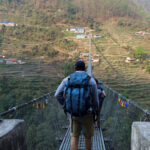 A Life Happens Outdoors community member crossing one of Nepal’s longest suspension bridges on the Annapurna Base Camp trek, surrounded by deep valleys and towering Himalayan peaks.