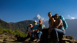 Trekker walking toward Chum Rung with Fishtail Mountain and Annapurna South rising behind under clear blue skies on the Annapurna Base Camp trail