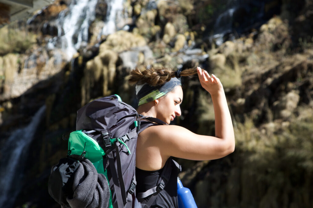 Close up of a Life Happens Outdoors community member with a waterfall behind her on the trail toward Machpucchare Fishtail Mountain in the Annapurna region
