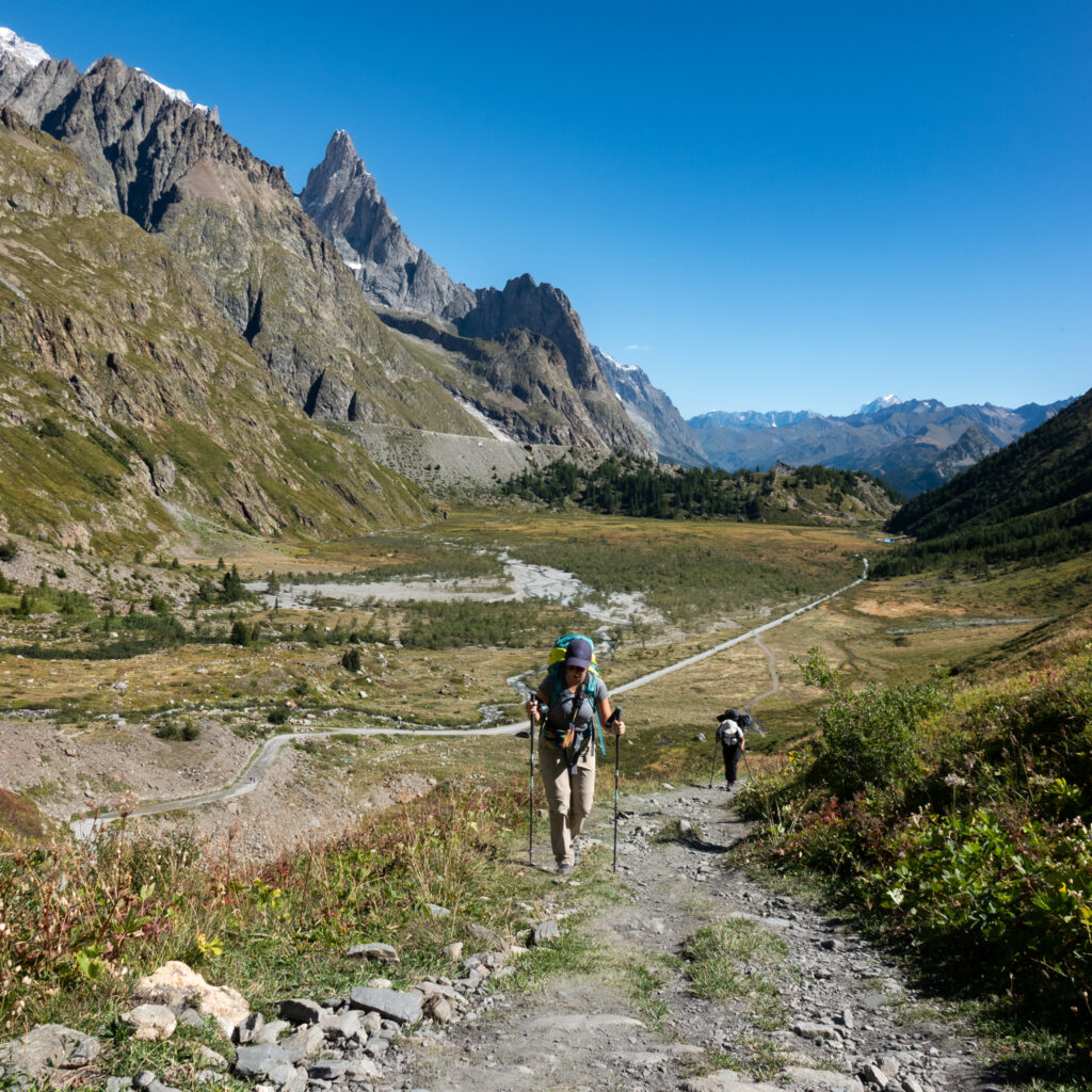 Life Happens Outdoors community member climbing toward a high pass on the Tour du Mont Blanc above Courmayeur with stunning valley views.