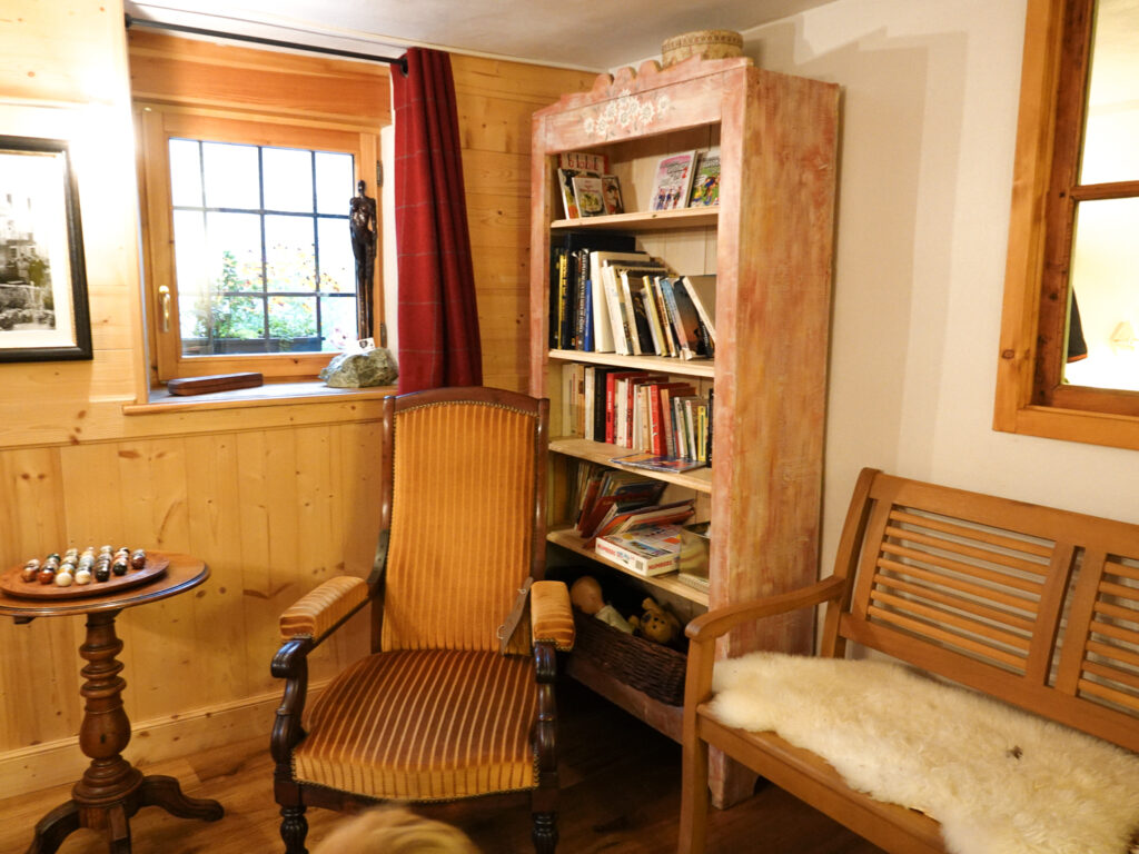 Cozy mountain refuge reading corner along the Tour du Mont Blanc with wooden interiors and books available to trekkers.