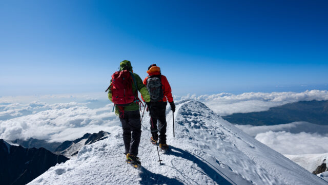 First time climber from the Life Happens Outdoors community descending Mont Blanc with the summit ridge and Bosses Ridge visible in ideal alpine conditions.