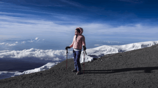 Life Happens Outdoors Community member on the Kilimanjaro crater rim with glaciers and blue sky during a clear summit day
