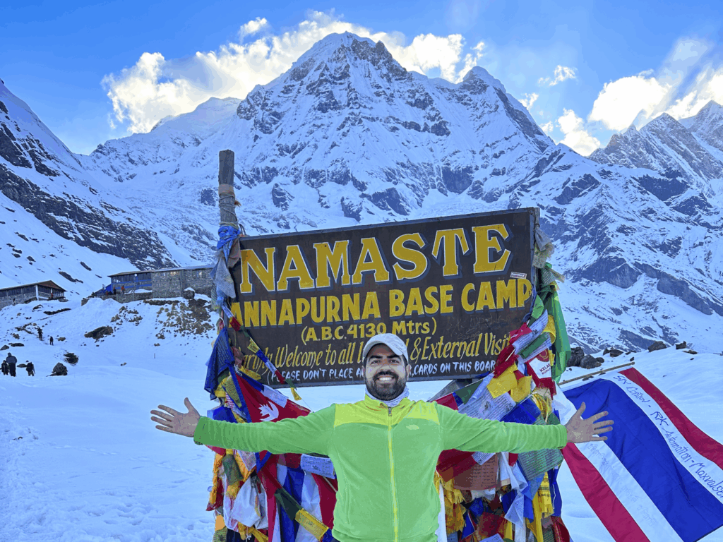 Life Happens Outdoors Team Leader Anthony Mizher at the Annapurna Base Camp sign with the Annapurna range behind him