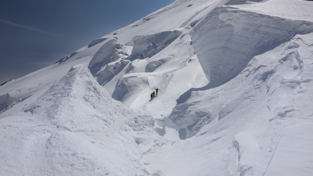 Three Life Happens Outdoors climbers on the Mont Blanc summit push, crossing the third boss in clear weather with glaciers all around
