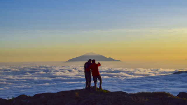 Two Life Happens Outdoors community members at Shira Camp on Kilimanjaro at sunset above a sea of clouds looking toward Mount Meru
