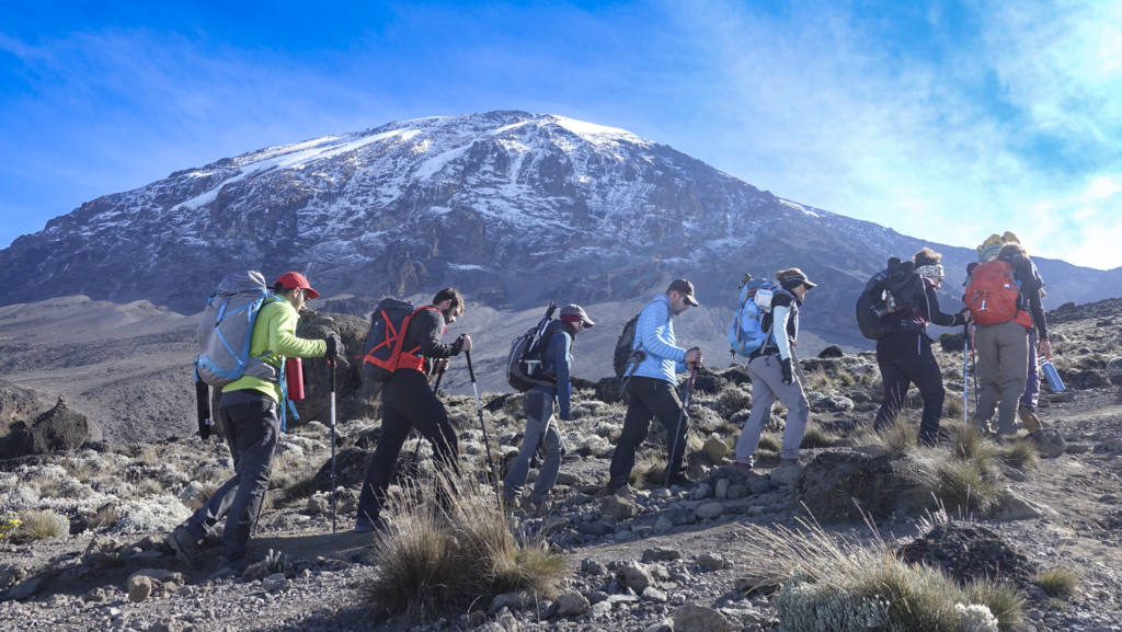 Life Happens Outdoors community members trekking toward Barafu Camp with the summit of Mount Kilimanjaro in the background
