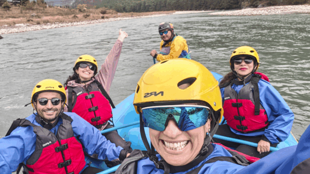 Life Happens Outdoors community members whitewater rafting in helmets and life jackets, smiling and bonding on the river
