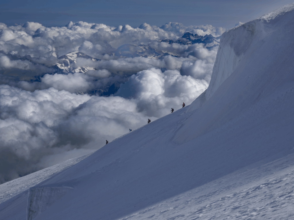 Life Happens Outdoors climbers descend the Dôme du Goûter above a sea of clouds on Mont Blanc