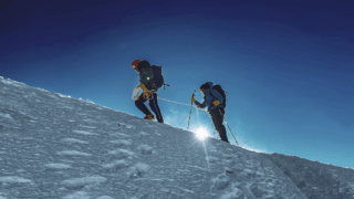 Life Happens Outdoors community member reaching the summit of a technical mountain in the Alps at sunrise.