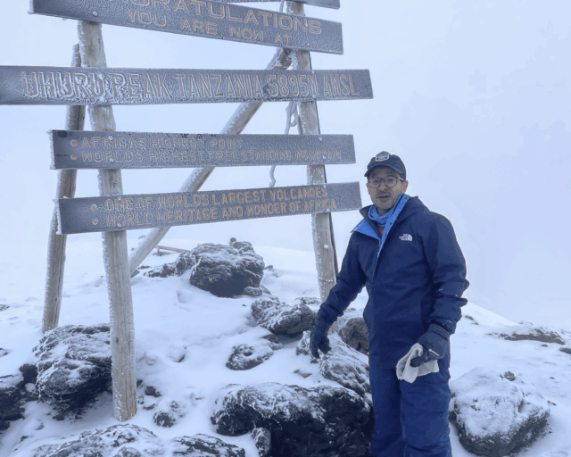Life Happens Outdoors community member celebrating on the summit of Kilimanjaro after a life changing climb.