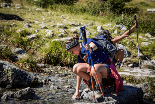 Life Happens Outdoors community member cooling her hands in a cold mountain stream during the Chamonix Valley Treks.