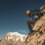 Life Happens Outdoors climber descending rocky terrain with Mont Blanc towering in the background, showing challenge and personal growth.
