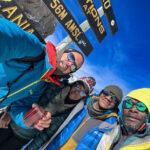 Life Happens Outdoors community members take a selfie at the Stella Point sign on the Kilimanjaro summit push moments before reaching Uhuru Peak.