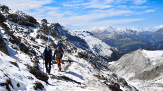 Guided group hiking a snowy mountain trail in the Alps