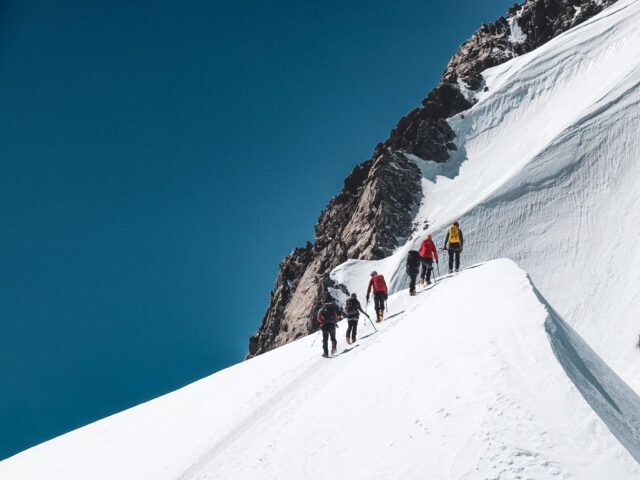Group of mountaineers ascending a snowy ridge during a guided climb in the Alps