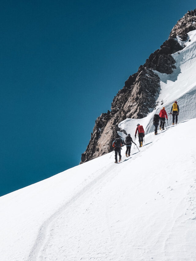 Group of mountaineers ascending a snowy ridge during a guided climb in the Alps