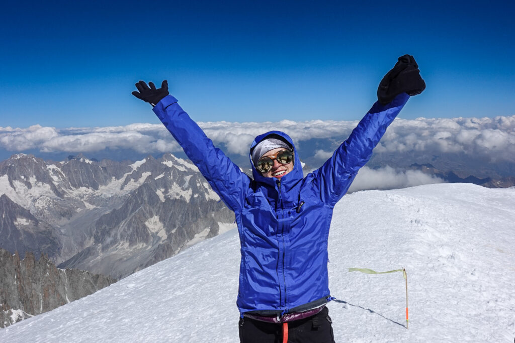 Traveler celebrating on a snowy mountain summit after a challenging climb