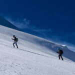 Two climbers ascending a snowy slope on Mont Blanc under a deep blue sky