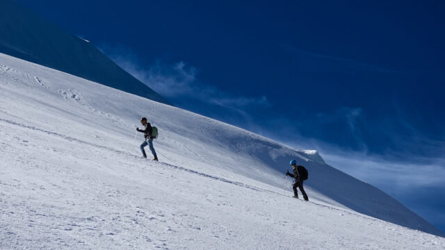 Two climbers ascending a snowy slope on Mont Blanc under a deep blue sky