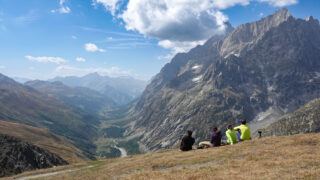 Guided hikers resting above an alpine valley during a hiking trip in the Alps