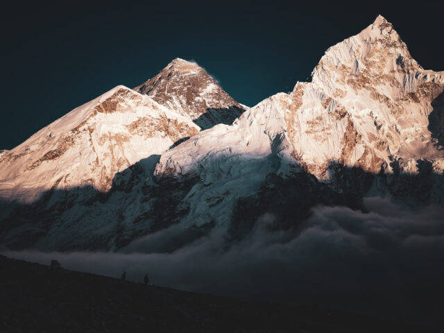 Sunrise light on snow covered Himalayan mountains above clouds in Nepal