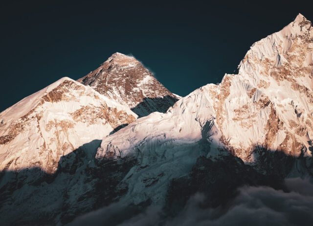 Sunrise light on snow covered Himalayan mountains above clouds in Nepal