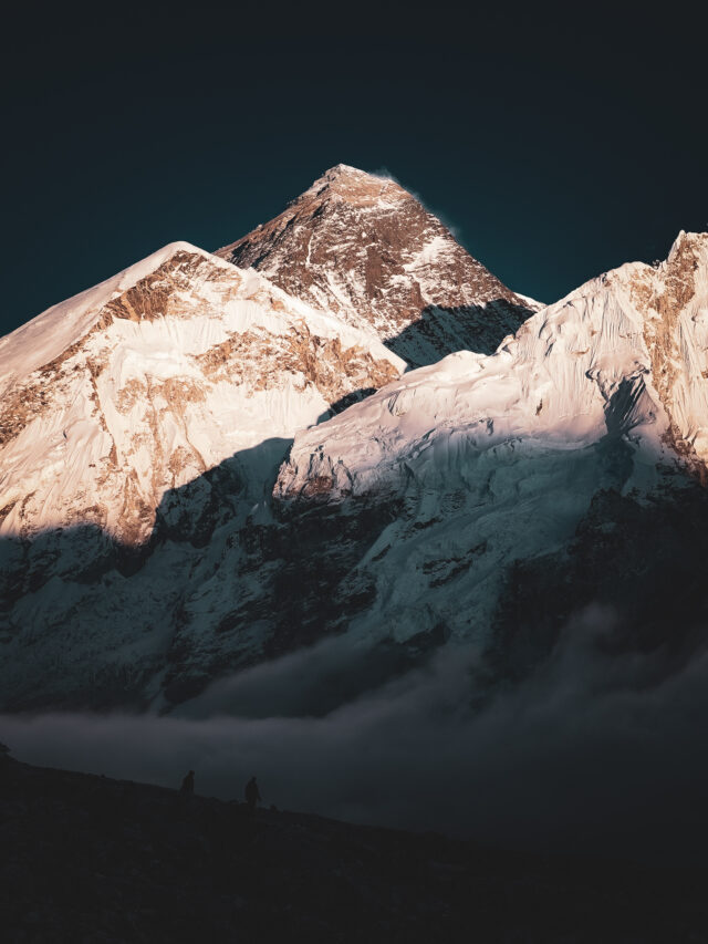 Vertical view of sunrise light on dramatic Himalayan mountains above clouds in Nepal