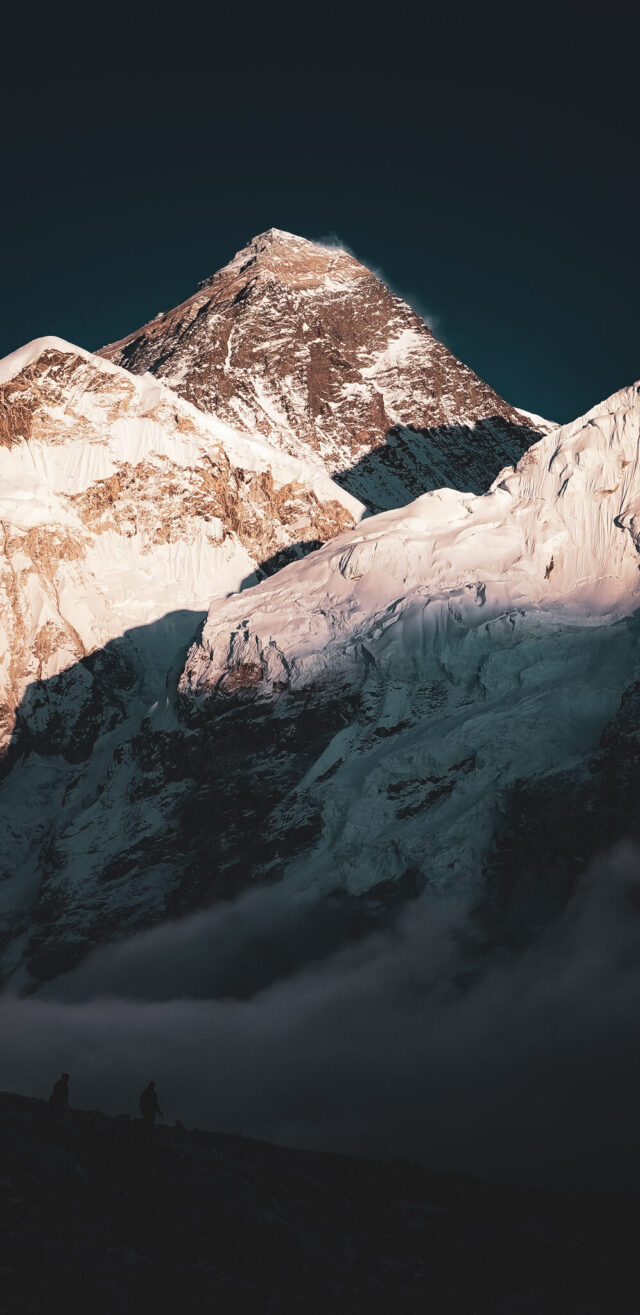 Vertical view of sunrise light on dramatic Himalayan mountains above clouds in Nepal